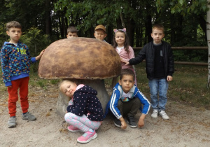 Dzieci stoją przy figurze grzyba.